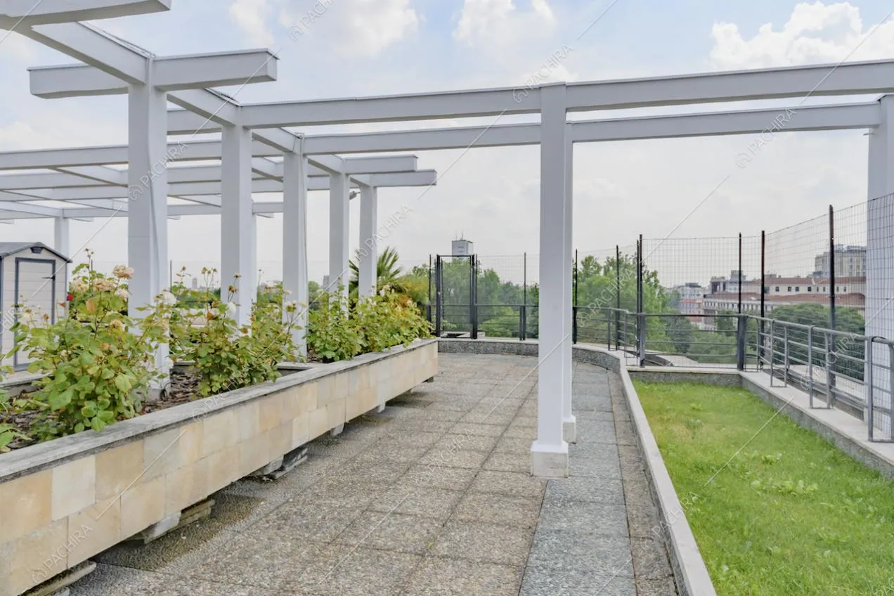 Aiuola e piante sull'ampia terrazza con vista su Milano e pergolato bianco