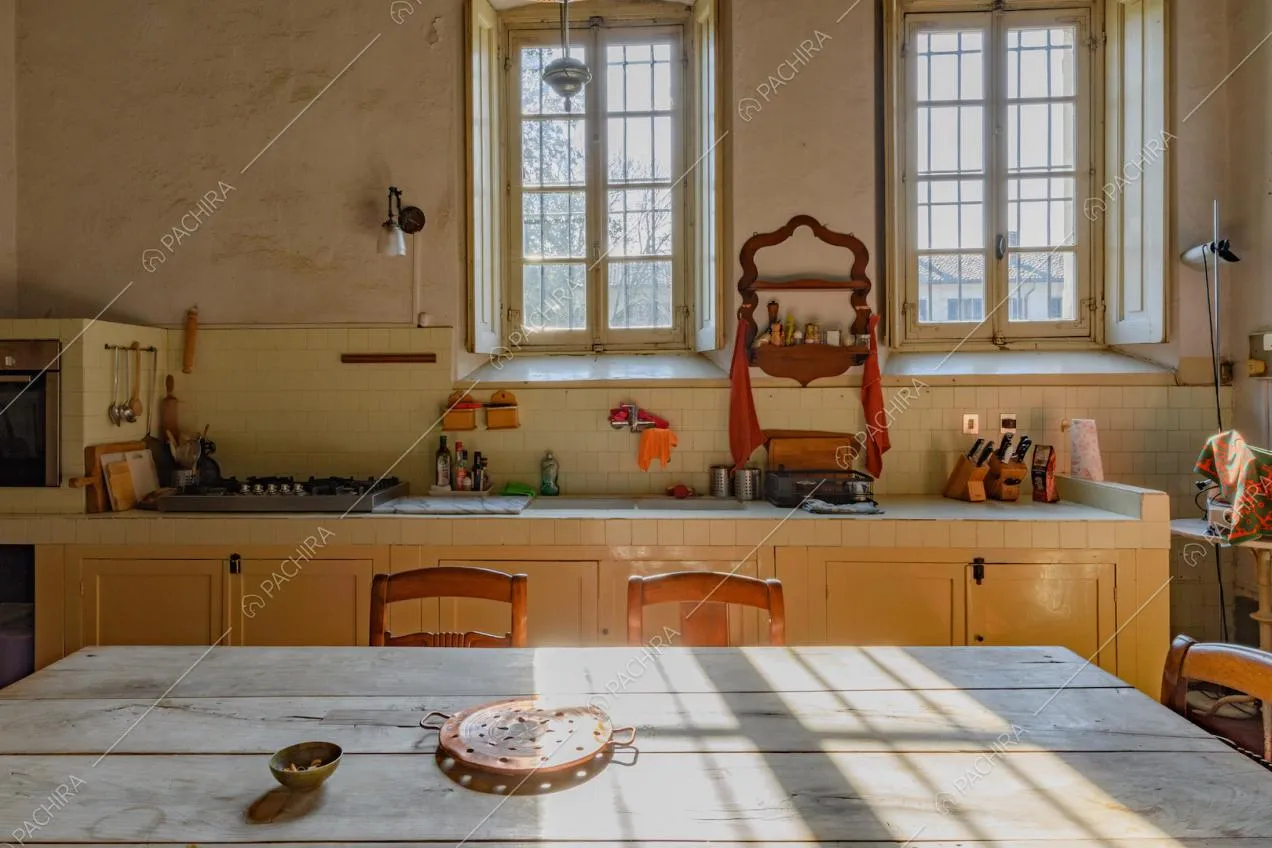 Tavolo da pranzo in legno nella luminosa cucina con fornelli a gas e paraschizzi in piastrelle