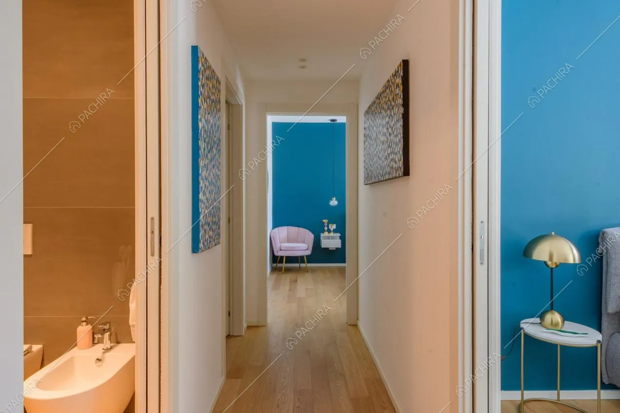 Lungo corridoio con pavimento in parquet e vista sul bagno e sulla camera da letto