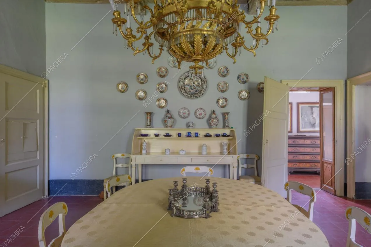 Grande sala da pranzo con lampadario dalle decorazioni dorate e pavimento in piastrelle rosse