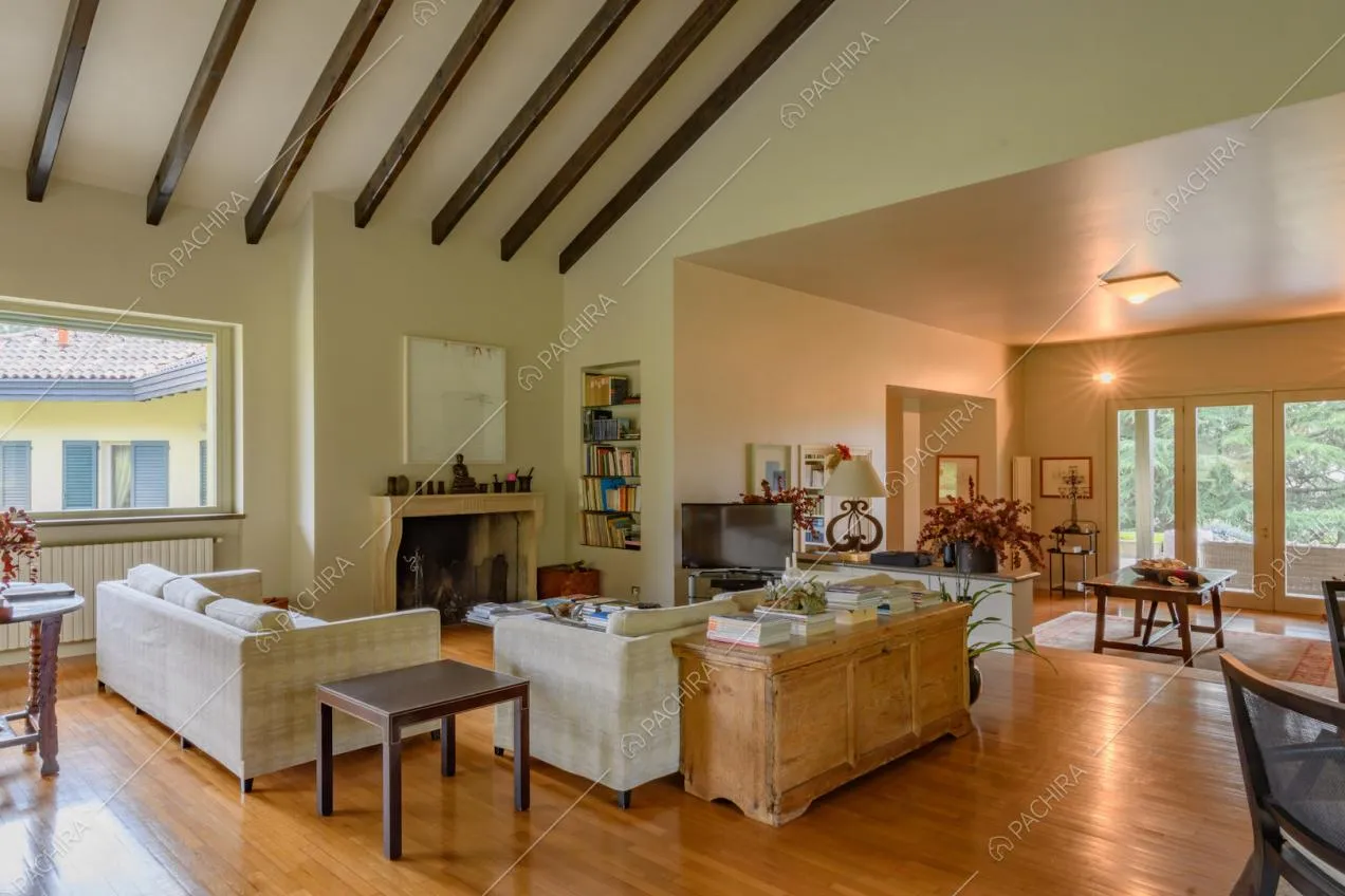Zona living con pavimento in parquet, vetrate, camino e travi in legno a vista