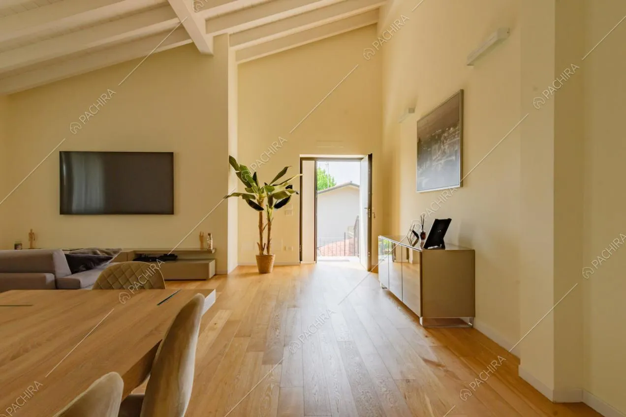 Luminosa zona living con pavimento in parquet, pareti gialle e travi a vista sul soffitto