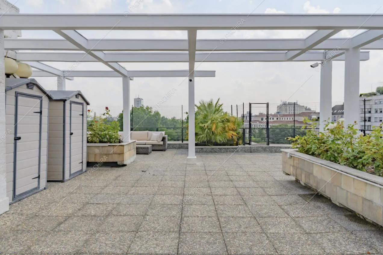Sulla grande terrazza con vista su Milano, cabine, pergolato bianco e piante