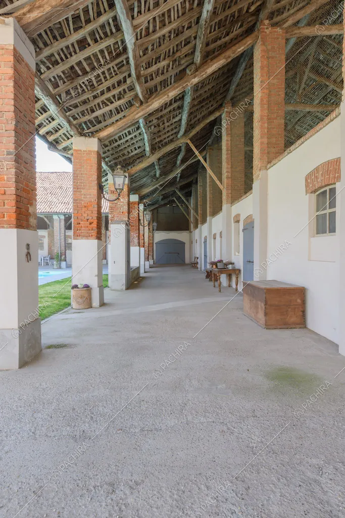 Grande porticolo con soffitto in legno e colonne bianche e in mattoni rossi a vista