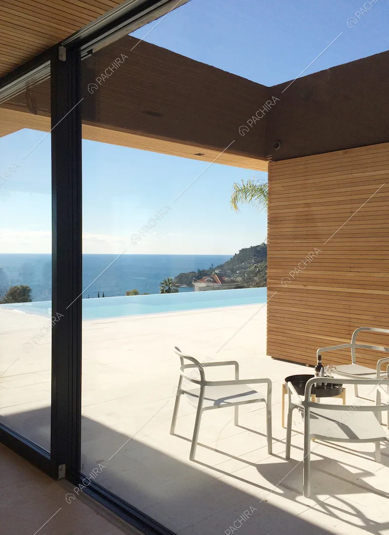 Dalla cucina, tramite la porta-finestra scorrevole, vista sulla terrazza con sedie da esterno e vista sul mare