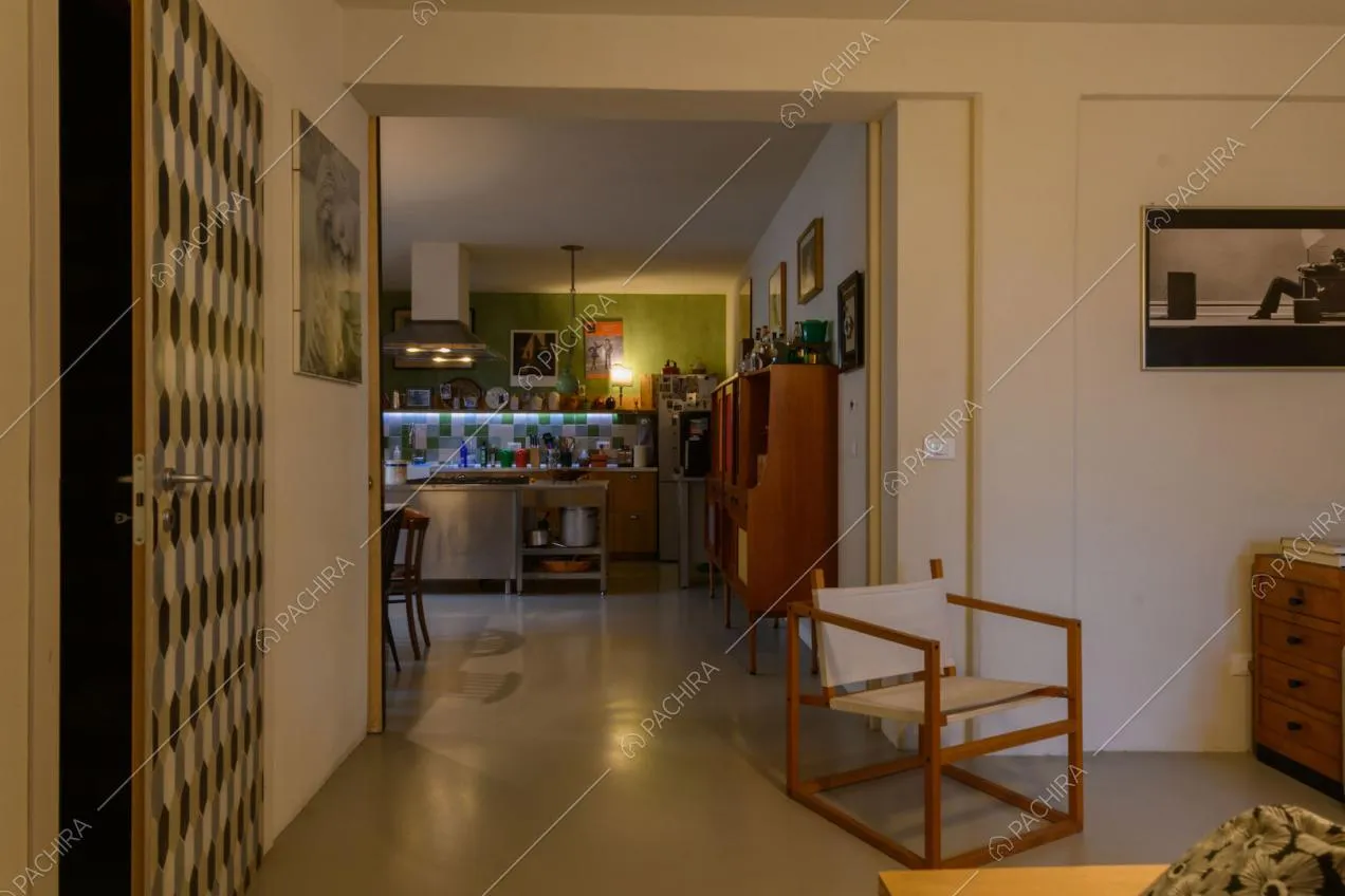 Vista sulla cucina con isola in acciaio e pavimento grigio in resina