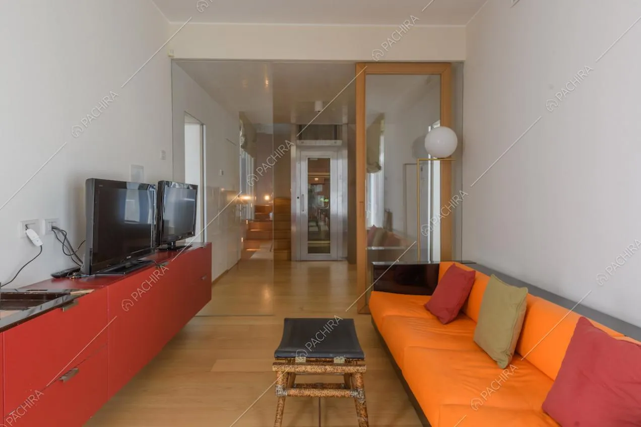 Studio con divano arancione e nero e pavimento in parquet