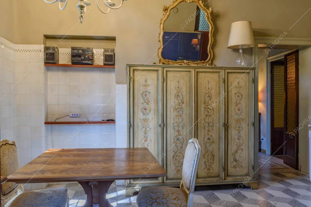 Cucina con tavolo da pranzo in legno, piastrelle bianche sulle pareti e armadio antico