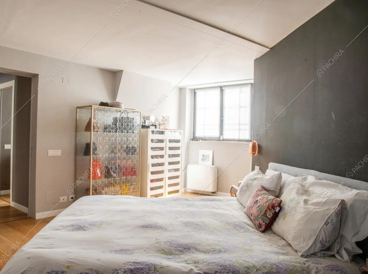 Letto matrimoniale nella camera con pareti grigie e pavimento in parquet