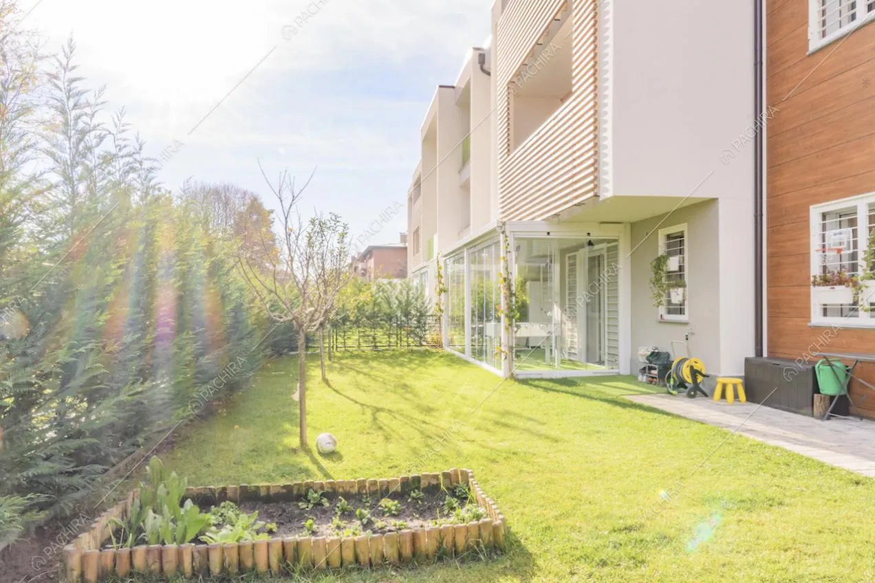 Piccola aiuola nel giardino e scorcio della veranda che funge da palestra