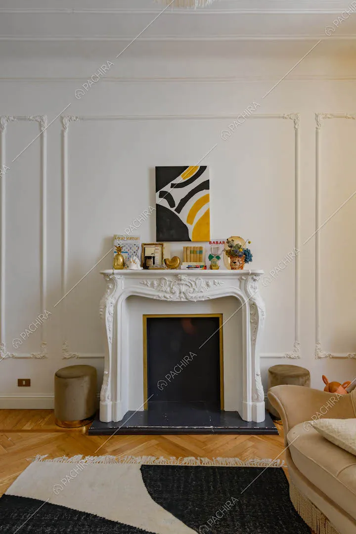 Camino con boiserie sulla cornice bianca, divano e pavimento in parquet a spina di pesce