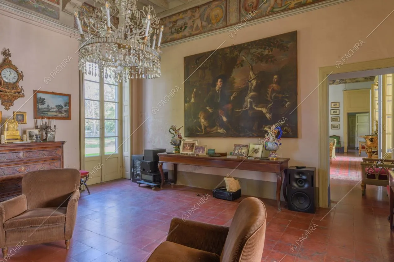 Salotto con pavimento in piastrelle rosse, lampadario in cristallo, dipinto e porta-finestra