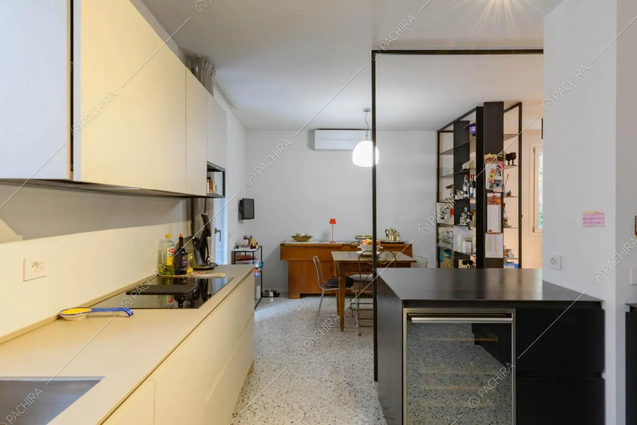 Dalla cucina con fornelli a induzione, pavimento in marmo e pareti bianche vista sul tavolo da pranzo