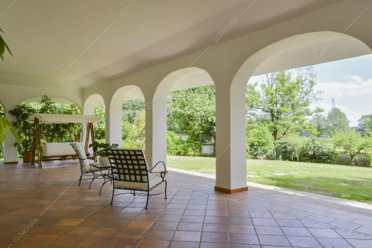 Poltrone e dondolo da esterno nella veranda con vista sul giardino