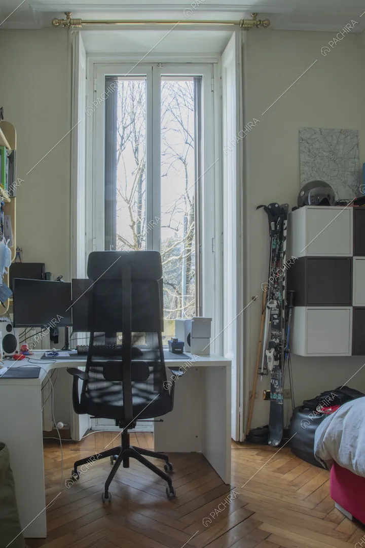 Scrivania con sedia ergonomica da ufficio davanti a una grande porta finestra