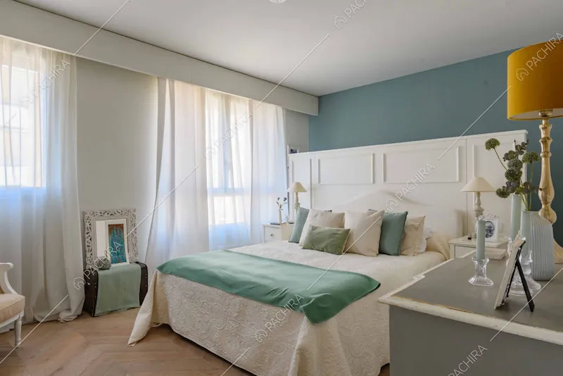 Camera da letto matrimoniale con parete blu e pavimento in parquet a spina di pesce