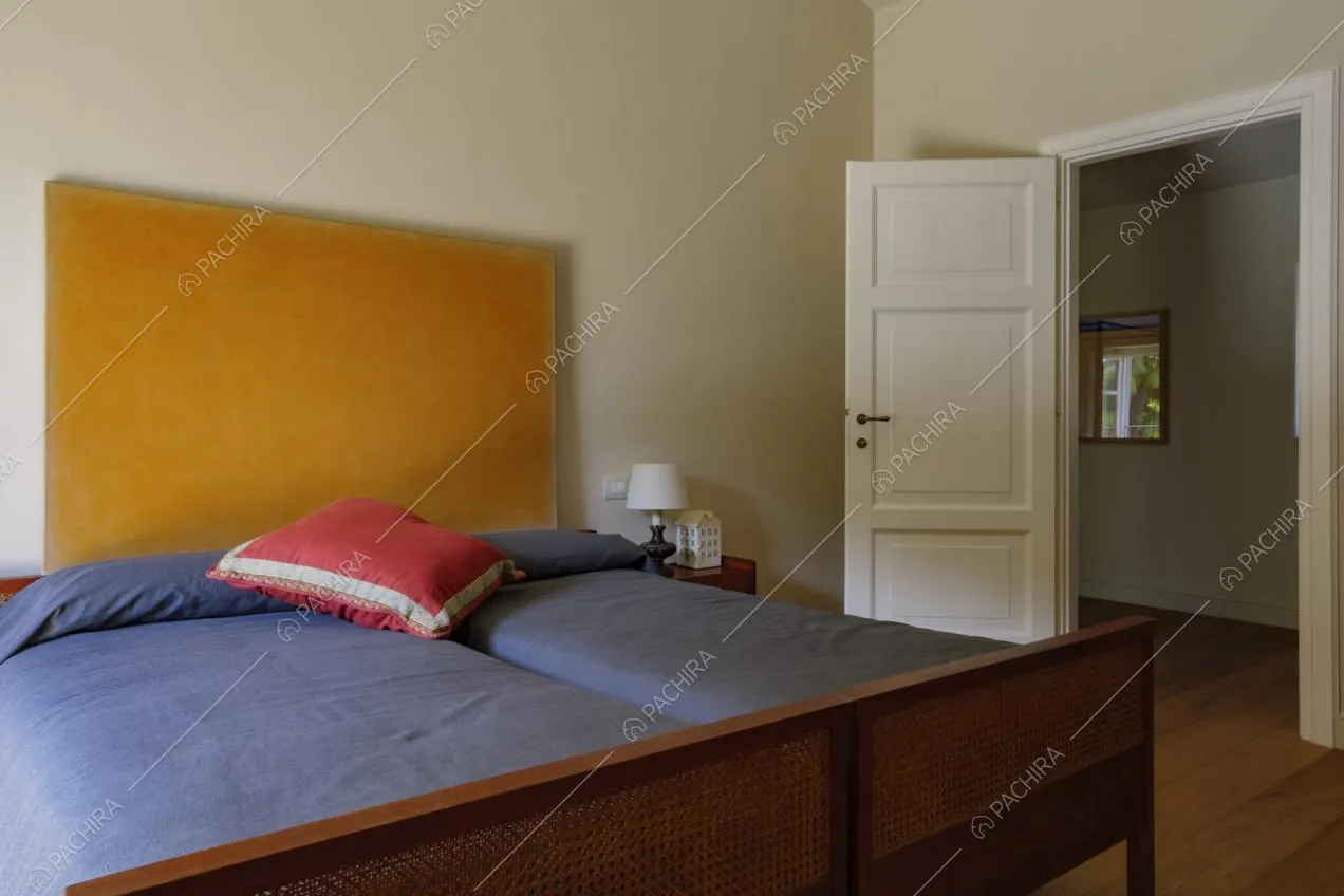 Letto matrimoniale con testa arancione nella camera con pavimento in parquet