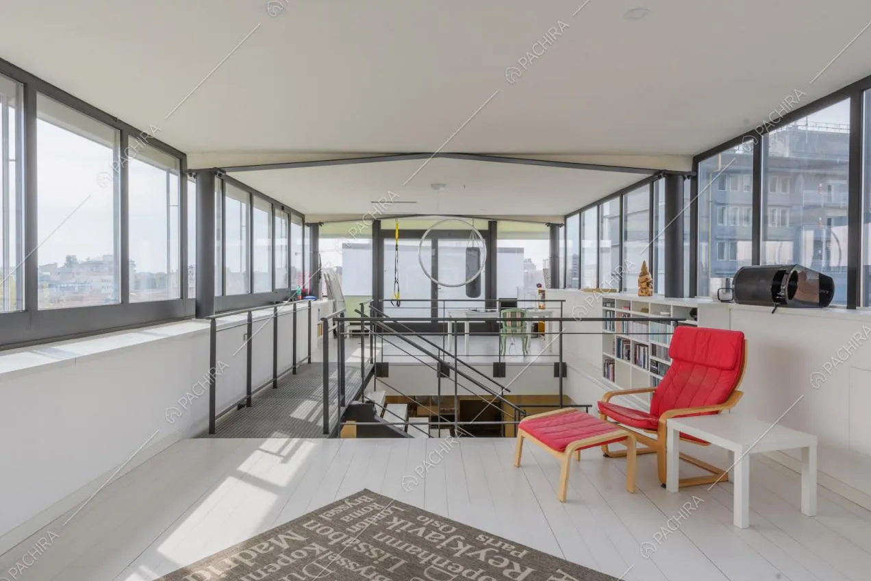 Pavimento in parquet bianco, poltrona di design e vetrate su ogni parete