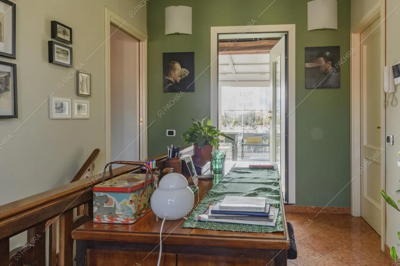 Parete verde con quadretti e mobile in legno