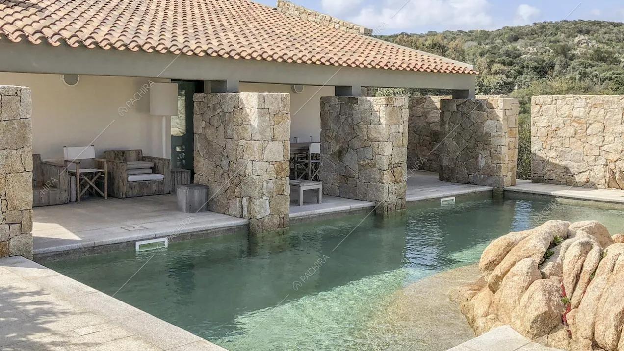 Piscina esterna di fianco al portico circondata da muri in pietra