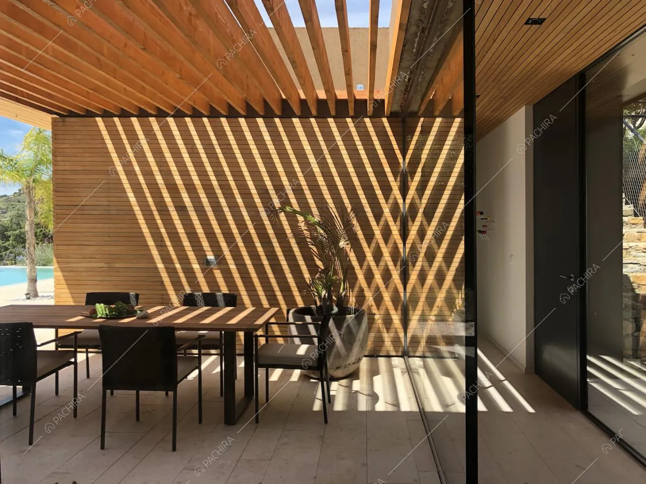 Veranda con tavolo da pranzo in legno da esterni, sedie nere e pavimento in lastre di pietra bianche
