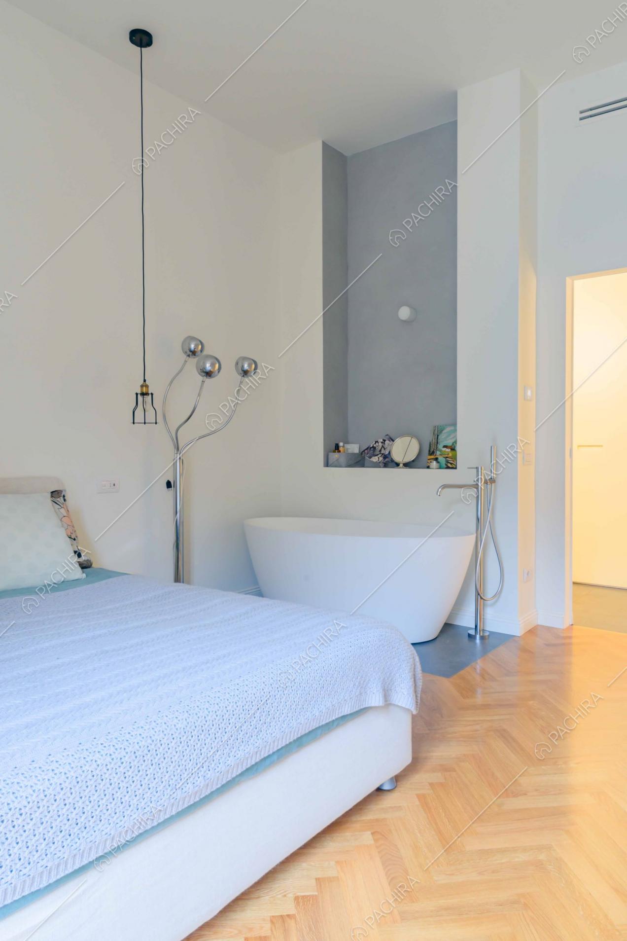 Camera da letto matrimoniale con vasca da bagno e pareti bianche