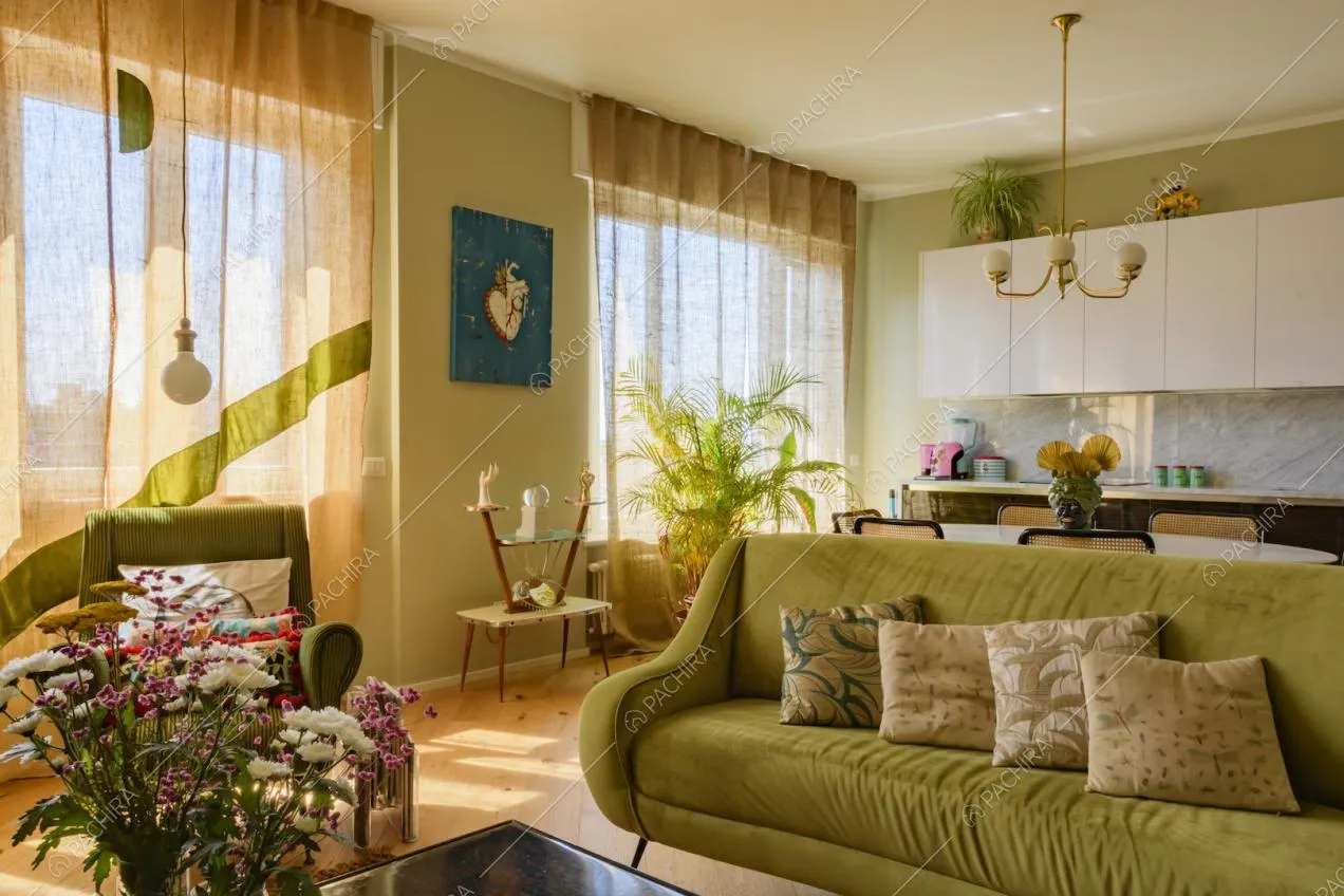 Divano in velluto verde con cuscini e cucina a parete
