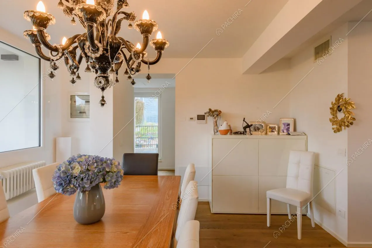 Sedie bianche e tavolo da pranzo in legno nella luminosa zona living con pavimento in parquet