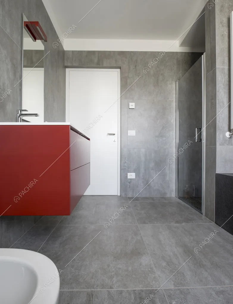 Bagno con piastrelle grigie su pavimento e pareti e mobile bagno rosso e sospeso