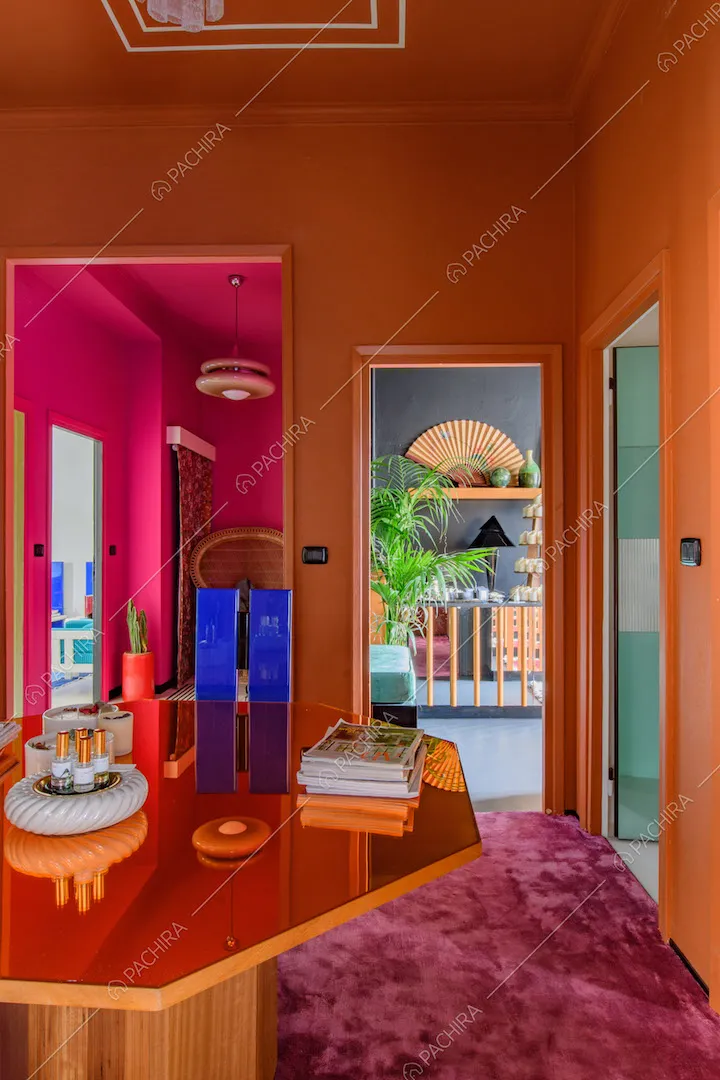 Tavolo ottagonale arancione a specchio nella sala con moquette fucsia sul pavimento