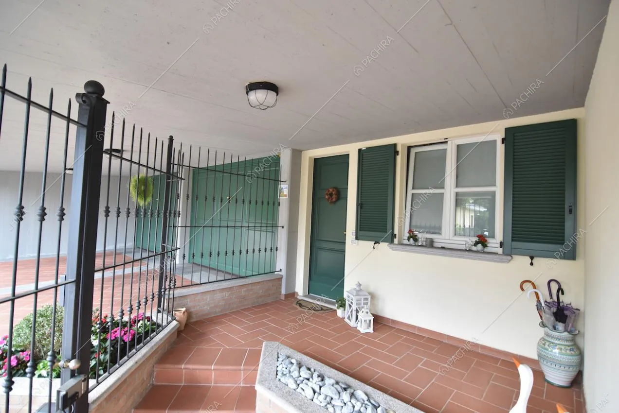 Angolo esterno della villa con ringhiera e finestre con persiane verdi