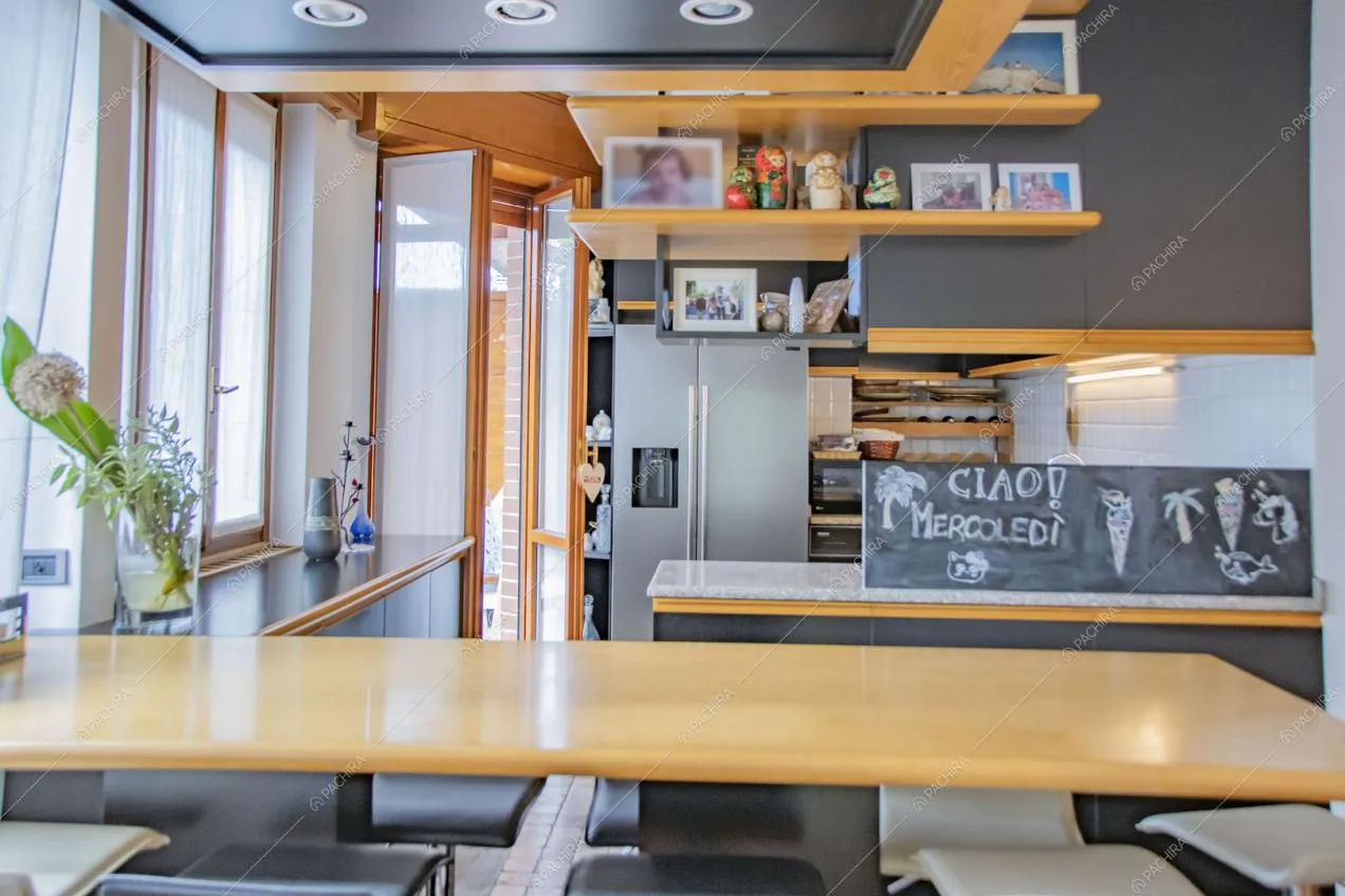 Bancone della cucina con sgabelli neri e bianchi e porta-finestra