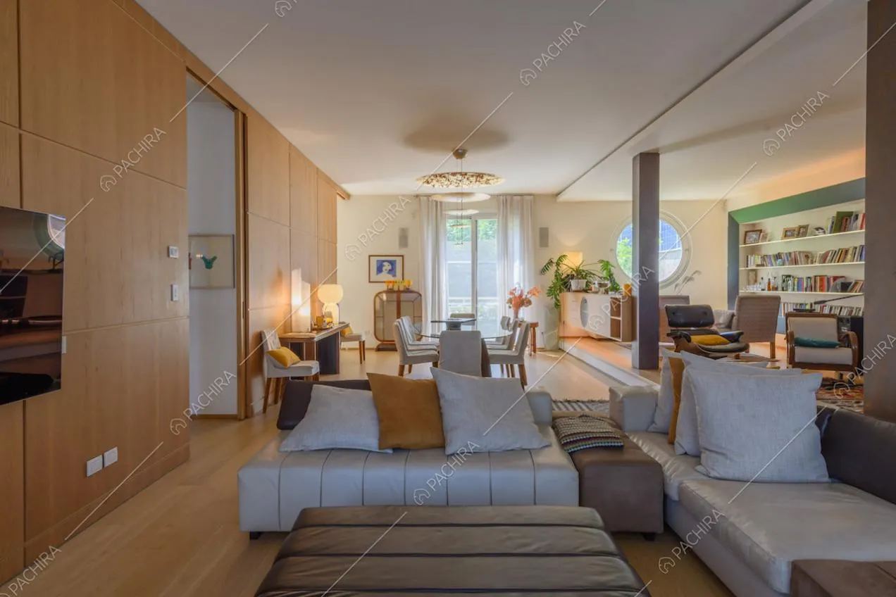 Divano angolare e pouf nella zona living con pareti in legno