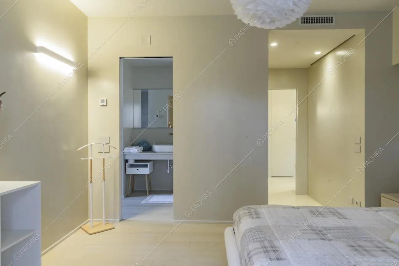 Camera da letto minimal con bagno privato, pavimento in parquet e pareti bianche