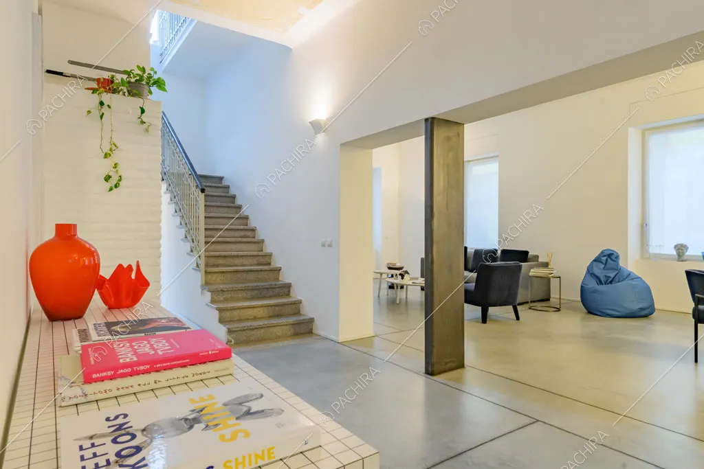 Tavolo di design con quadrati bianchi nel grande atrio con vista su scale e sala
