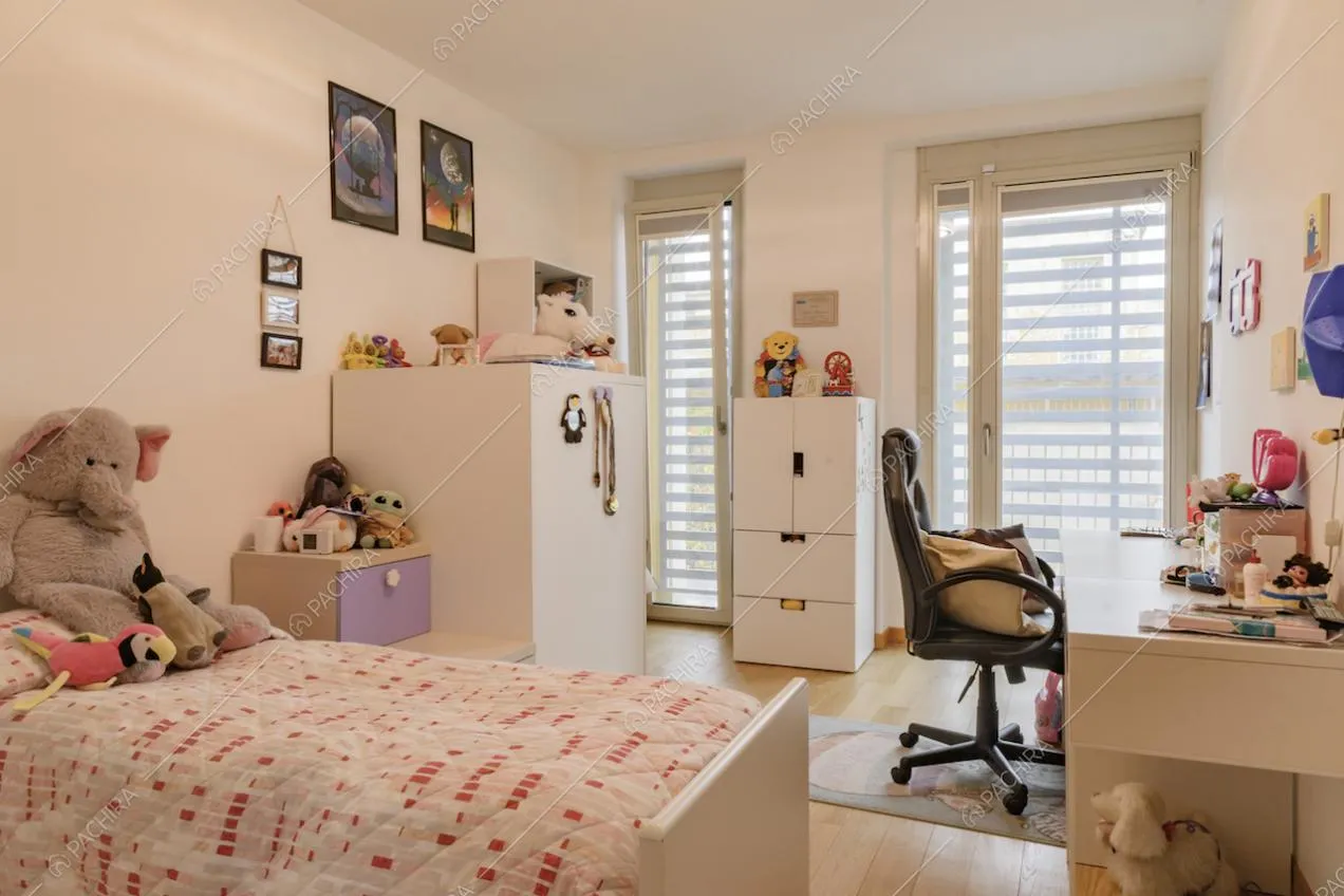 Cameretta da bambini dai toni caldi con scrivania e pavimento in parquet