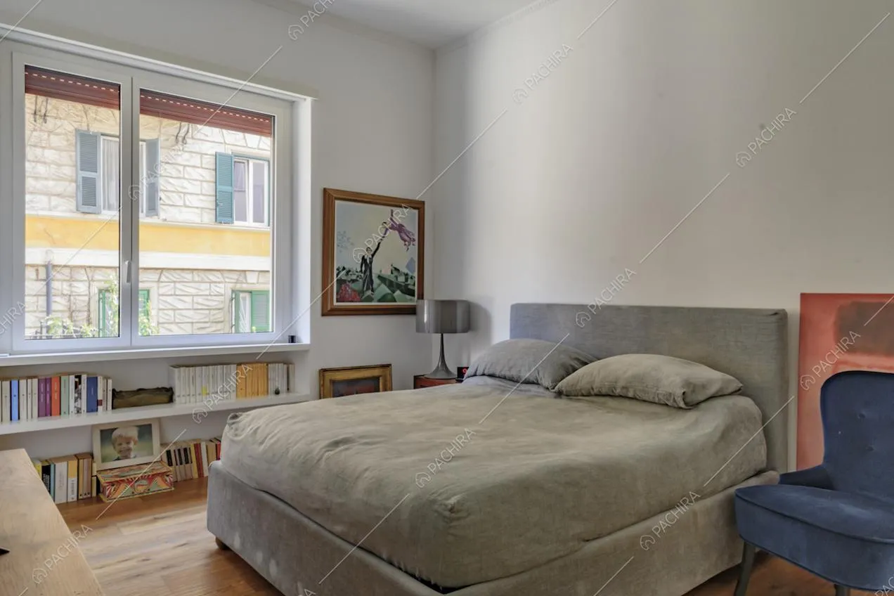 Luminosa camera da letto matrimoniale dalle pareti bianche e con pavimento in parquet