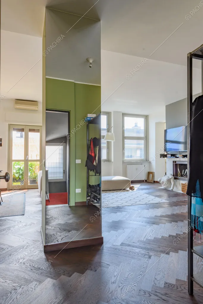 Colonna con specchio a tutta parete nella zona living con pavimento in parquet
