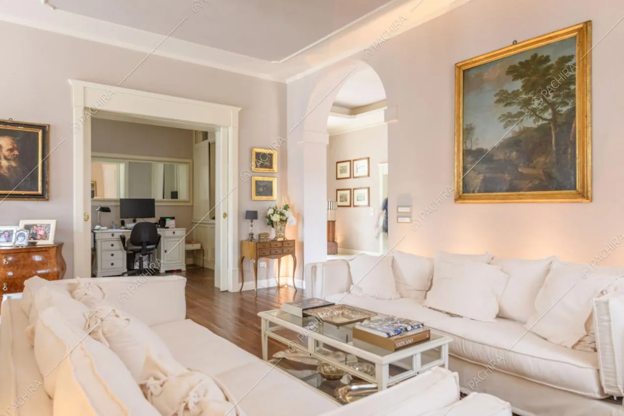 Divani bianchi nella luminosa zona living con pavimento in parquet e vista sullo studio