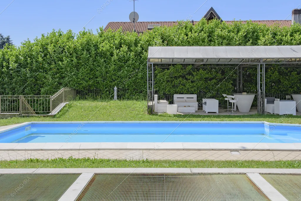 Giardino con piscina e gazebo con divanetti e tavolini