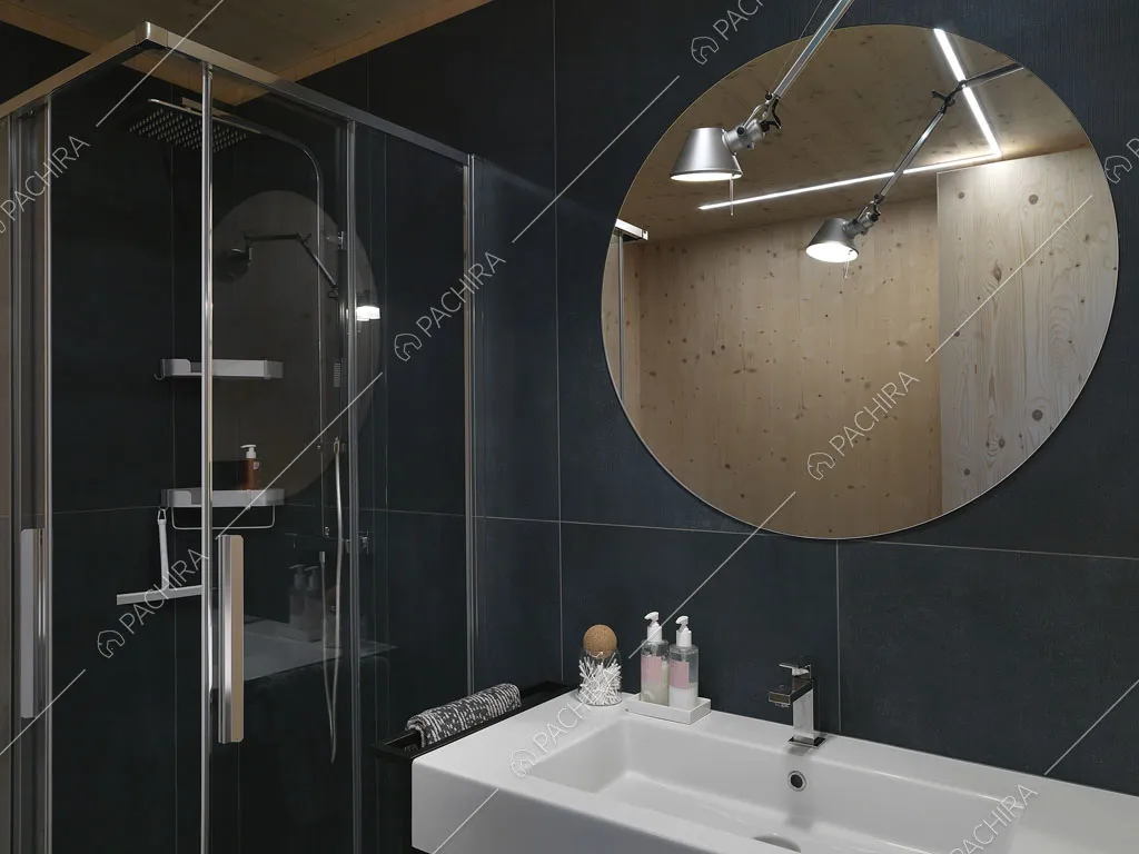 Bagno con box-doccia, pareti in grandi piastrelle nere e specchio rotondo