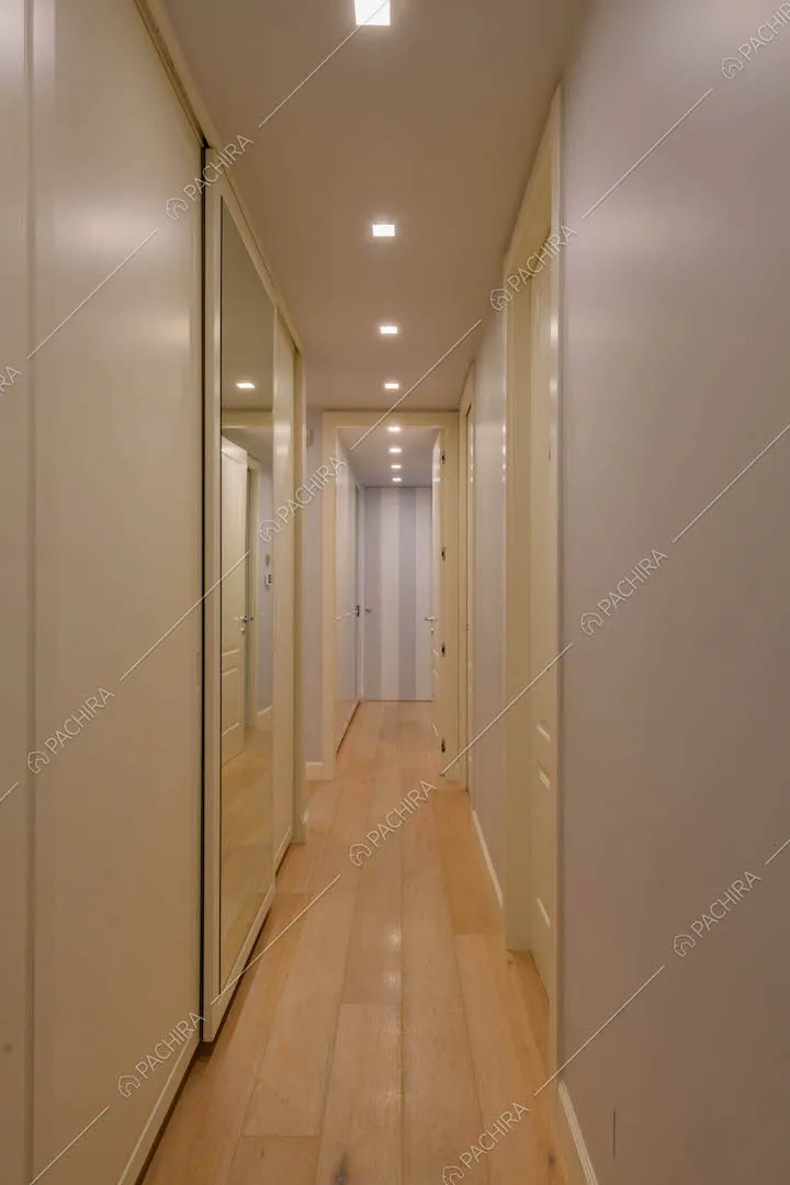 Luminoso corridoio con pavimento in parquet e porte bianche