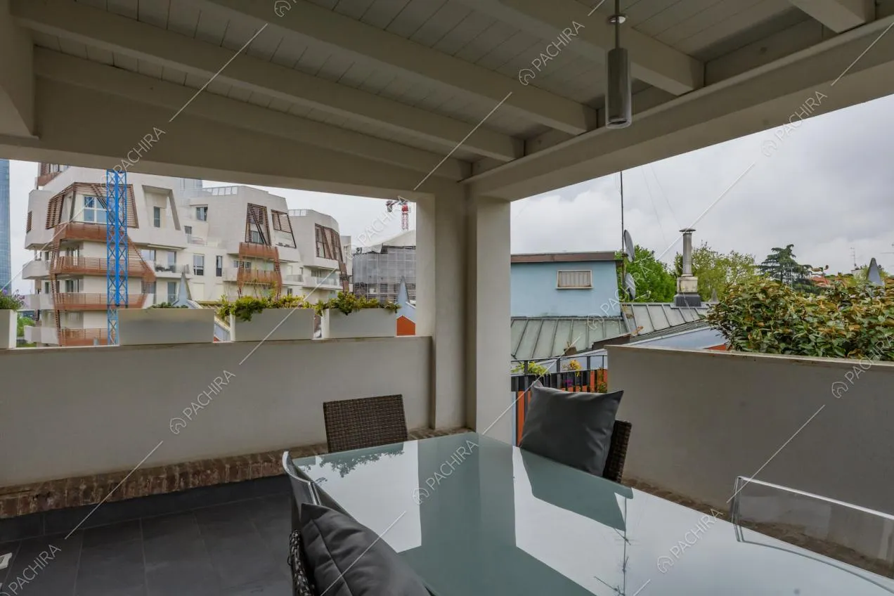 Tavolo da pranzo in vetro sulla veranda con soffitto in travi in legno a vista
