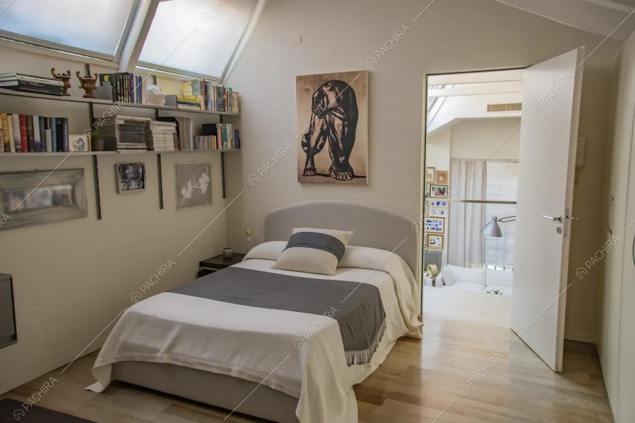 Letto singolo con pareti chiare e quadro appeso sopra alla testata