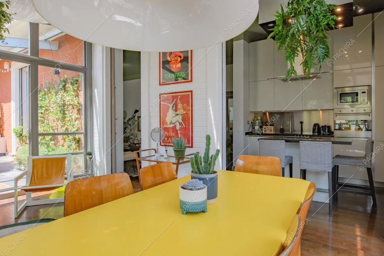 Cucina bianca a vista con isola, pavimento in parquet e tavolo da pranzo giallo