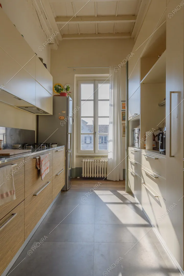 Luminosa cucina a parete con soffitto bianco a cassettoni e fornelli a gas