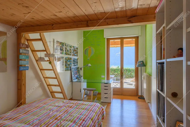 Camera da letto dei bambini con parete verde, soppalco e porta-finestra