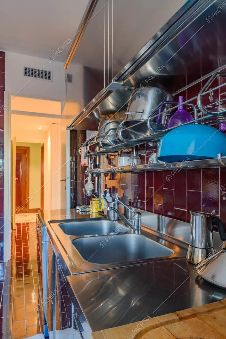 Tavolo da lavoro nella cucina con pareti e pavimento in piastrelle rosse lucide