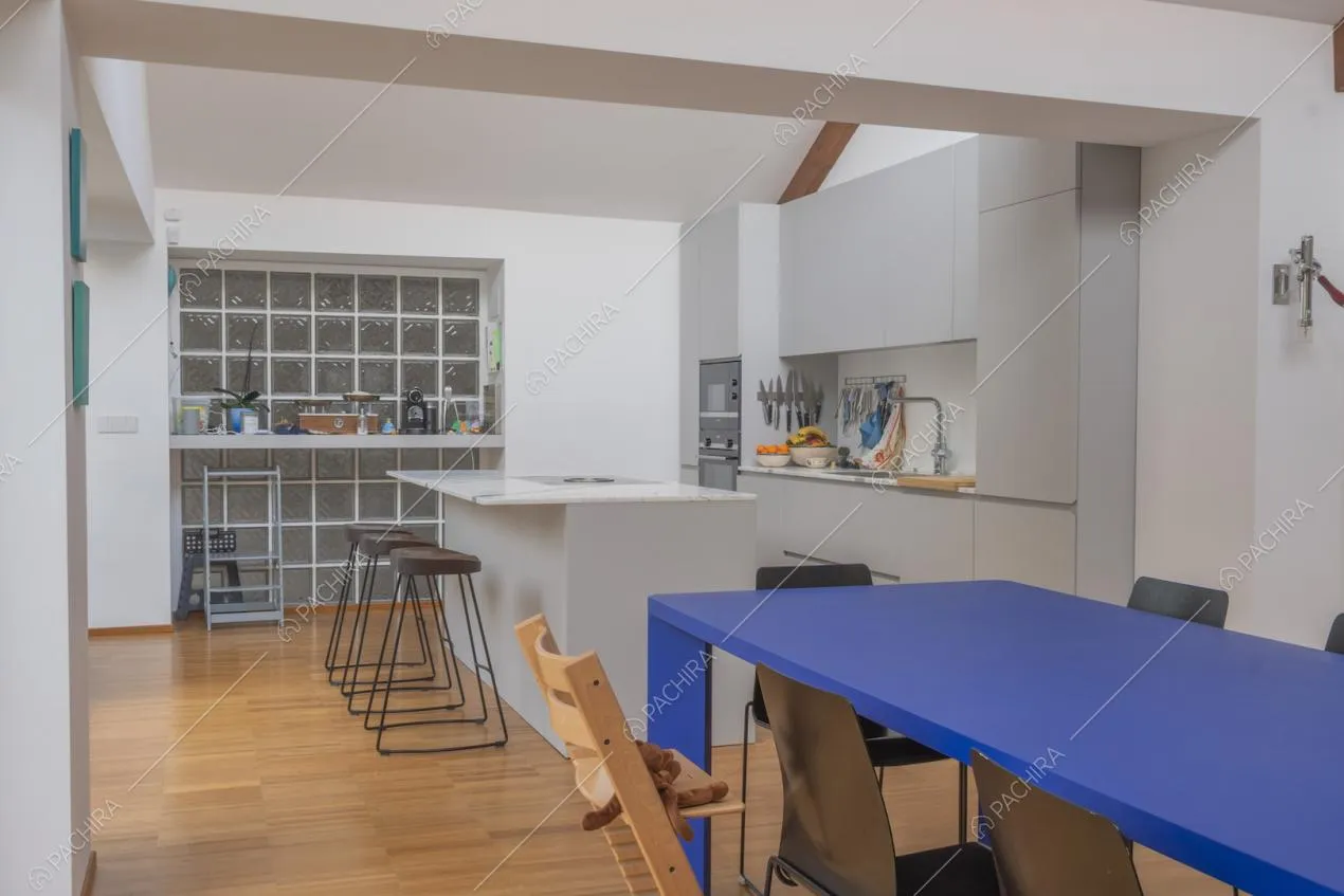 Cucina a isola bianca con sgabelli alti, pavimento in parquet e tavolo da pranzo