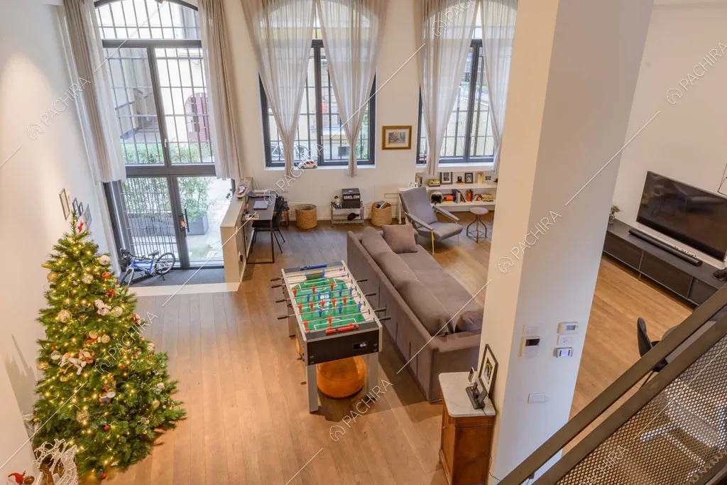 Dal soppalco vista sulla zona living con pavimento in parquet e finestre industriali